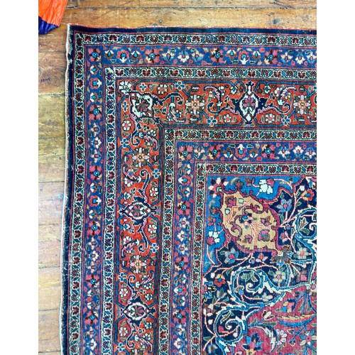 135 - A large Persian hand-knotted medallion carpet worked with deep rouge and reds, stylised floral spand... 