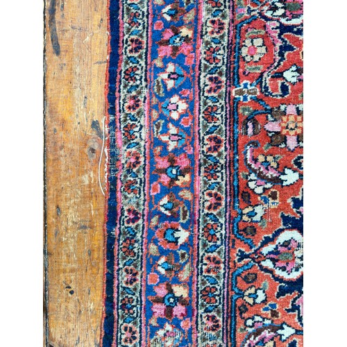 135 - A large Persian hand-knotted medallion carpet worked with deep rouge and reds, stylised floral spand... 