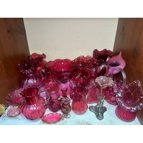 64 - A very large collection of assorted Cranberry coloured glass, comprising jugs, vases, bowls, etc., i... 