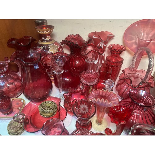 64 - A very large collection of assorted Cranberry coloured glass, comprising jugs, vases, bowls, etc., i... 