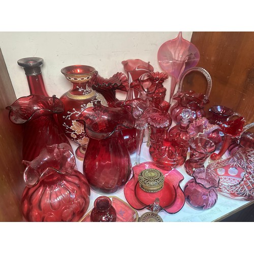 64 - A very large collection of assorted Cranberry coloured glass, comprising jugs, vases, bowls, etc., i... 