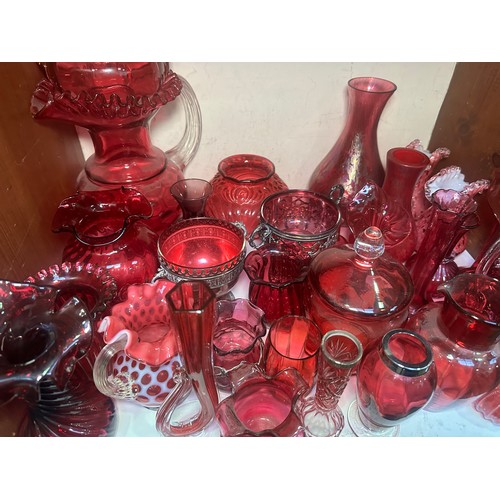 64 - A very large collection of assorted Cranberry coloured glass, comprising jugs, vases, bowls, etc., i... 