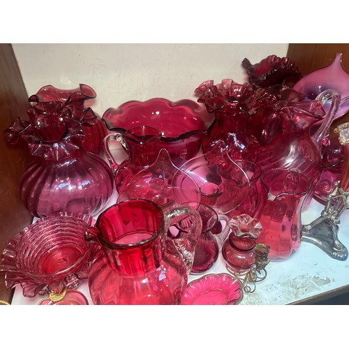 64 - A very large collection of assorted Cranberry coloured glass, comprising jugs, vases, bowls, etc., i... 