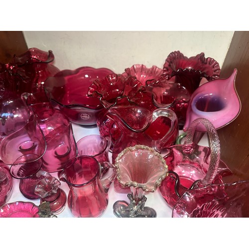 64 - A very large collection of assorted Cranberry coloured glass, comprising jugs, vases, bowls, etc., i... 