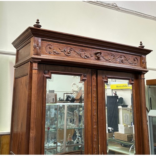 651 - A French oak armoire, the cornice with carved frieze, above a pair of mirrored doors, flanked by flu... 