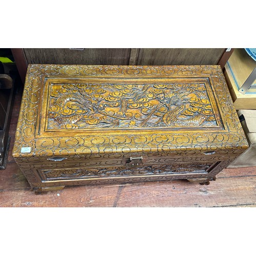 545 - A Chinese carved, camphor lined trunk, the lid, front and sides carved with dragons, raised on shape... 