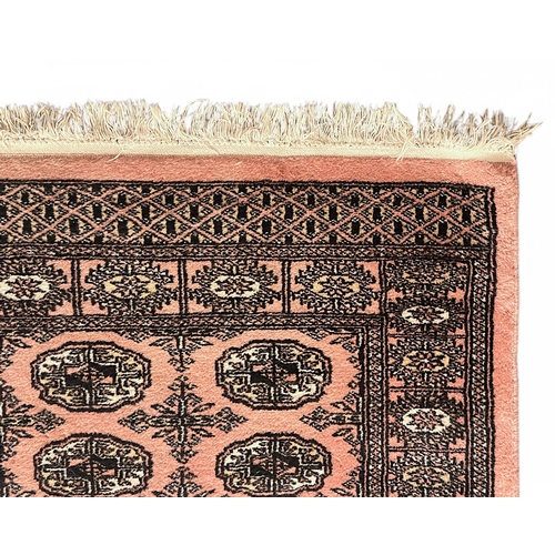 490 - A hand-knotted woollen rug of Caucasian design, worked with stylised guls to a salmon pink ground, 7... 