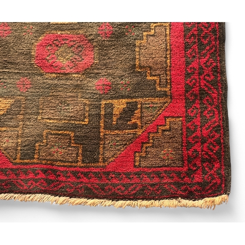 492 - A hand-knotted woollen rug of Caucasian design, worked with two large guls to a red ground within a ... 