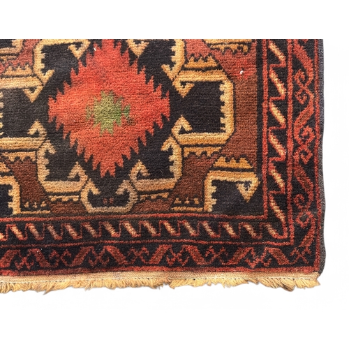 493 - A hand-knotted woollen tribal rug of Caucasian design, worked with stylised guls to a brick red grou... 