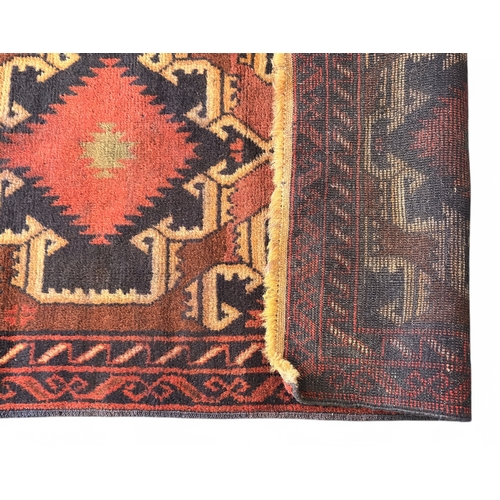 493 - A hand-knotted woollen tribal rug of Caucasian design, worked with stylised guls to a brick red grou... 