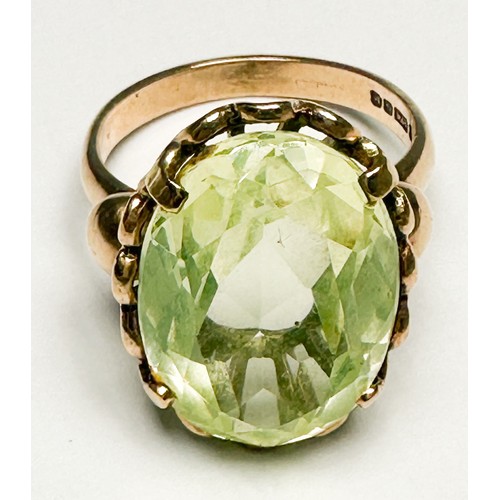 250 - A 9ct gold dress ring, claw set in a foliate design shank with a large oval faceted pale green stone... 