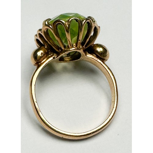 250 - A 9ct gold dress ring, claw set in a foliate design shank with a large oval faceted pale green stone... 