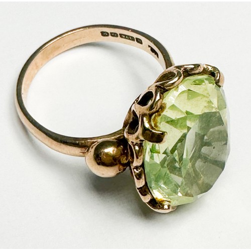 250 - A 9ct gold dress ring, claw set in a foliate design shank with a large oval faceted pale green stone... 