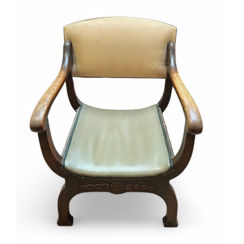 588 - An oak X-frame armchair, with cream damask upholstered back and green vinyl close-nailed seat.