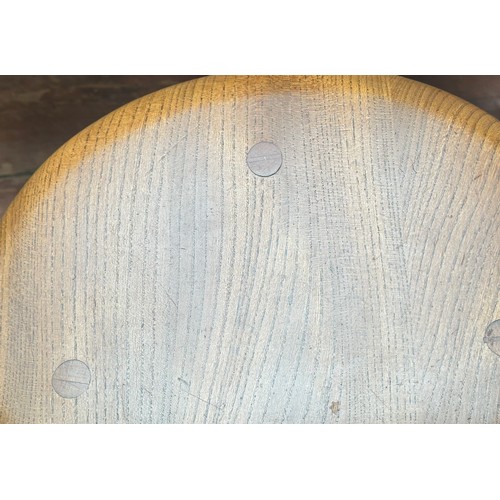 560 - A nest of three blonde elm, Ercol pebble occasional tables, largest measures 65cm diameter.