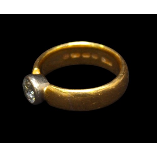 A 22ct gold wedding band cut and bezel-set with a solitaire diamond ...