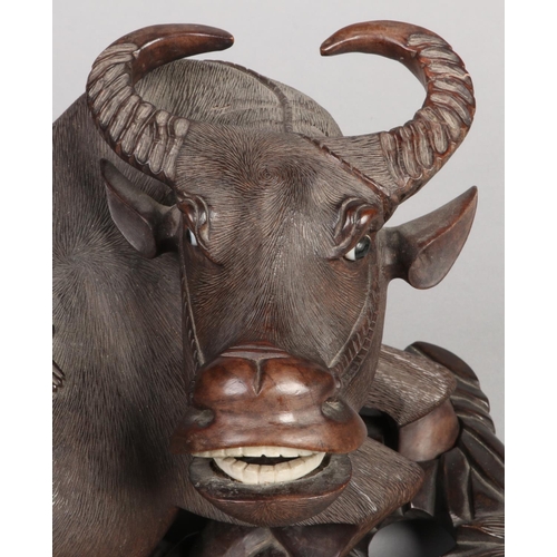 202 - A 19th century Chinese carved hardwood sculpture of a water buffalo with a young boy riding upon its... 