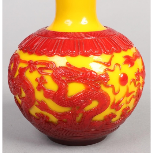 219 - A Chinese Peking glass bottle vase. Red overlay on a yellow ground depicting dragons chasing a flami... 