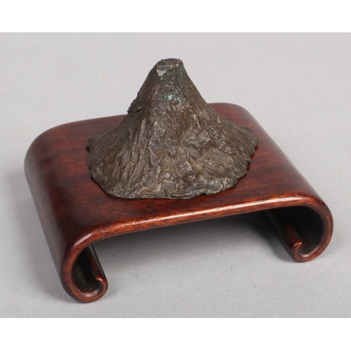 242 - A 19th century Chinese bronze scholars scroll weight formed as a mountain and raised on a hardwood p... 