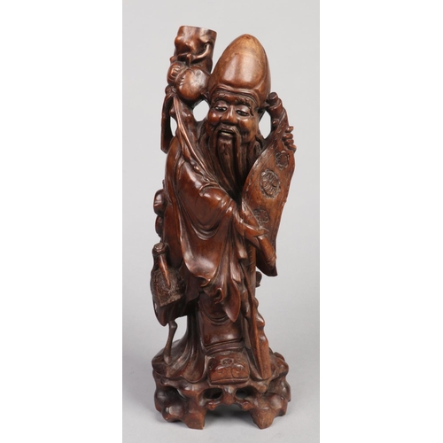 246 - An early 20th century Chinese carved hardwood figural tablelamp base formed as a sage. Stood holding... 