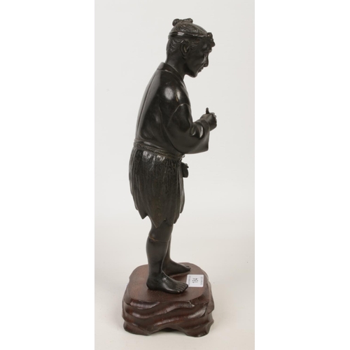 184 - A Japanese Meiji period bronze statue raised on a wooden plinth. Formed as a man holding a pipe and ... 