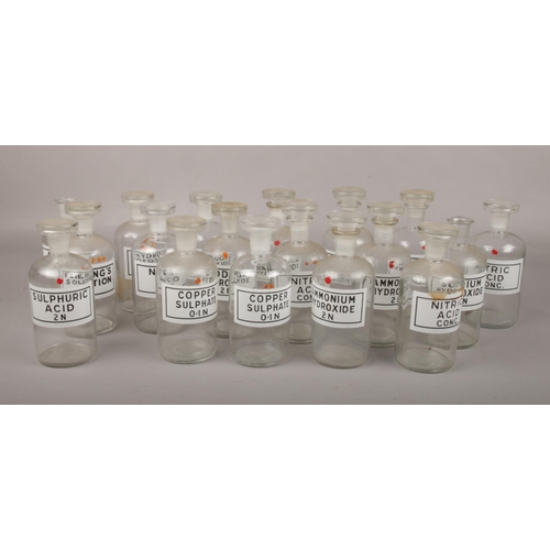 67 - 18 vintage laboratory glass chemical storage bottles and stoppers with printed labels.