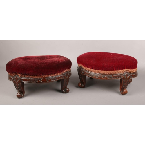 733 - A pair of Victorian carved walnut oval footstools. With overstuffed velvet upholstery and raised on ... 