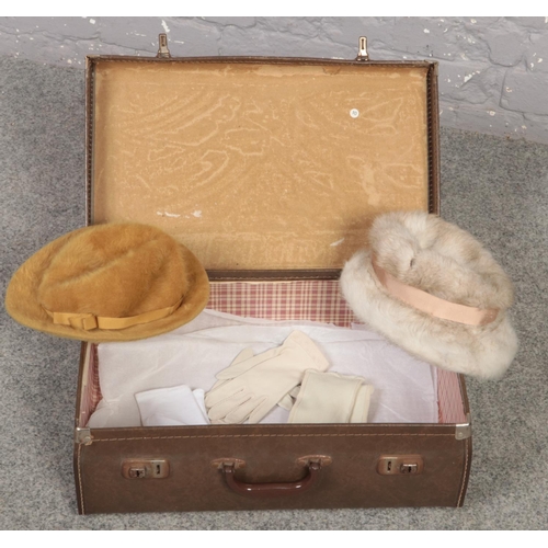 590 - A vintage suitcase to include two ladies hats and gloves