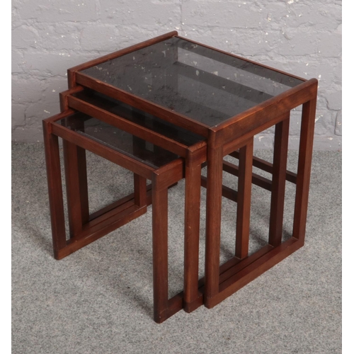 637 - A nest of three teak occasional tables with smoked glass tops c.1970s