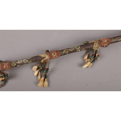 147 - An African tribal witch doctor stick, with animal tooth and pigment decoration. (Length 94cm).