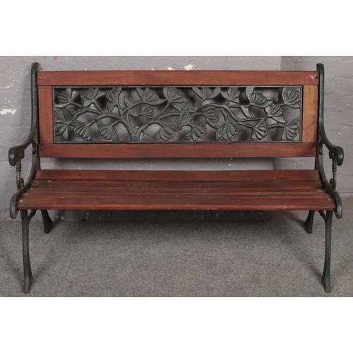 596 - A wood and cast iron garden bench with floral back decoration.