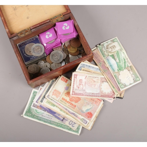 87 - A wooden box with contents of British pre decimal and world coins and banknotes, to include commemor... 