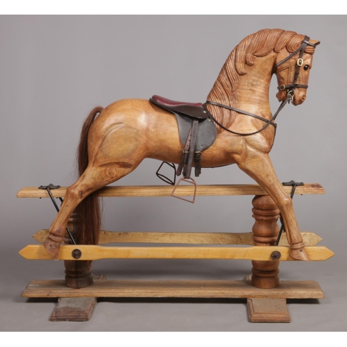 253 - A large carved hardwood child's rocking horse with leather saddle and bridle, 105cm high.