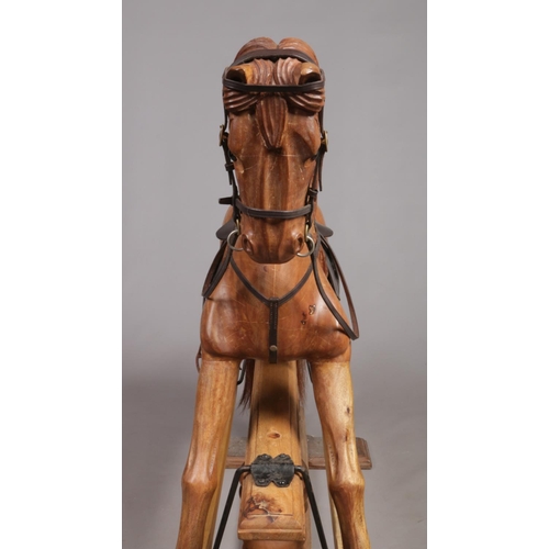 253 - A large carved hardwood child's rocking horse with leather saddle and bridle, 105cm high.