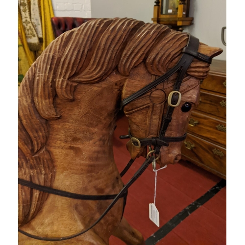 253 - A large carved hardwood child's rocking horse with leather saddle and bridle, 105cm high.