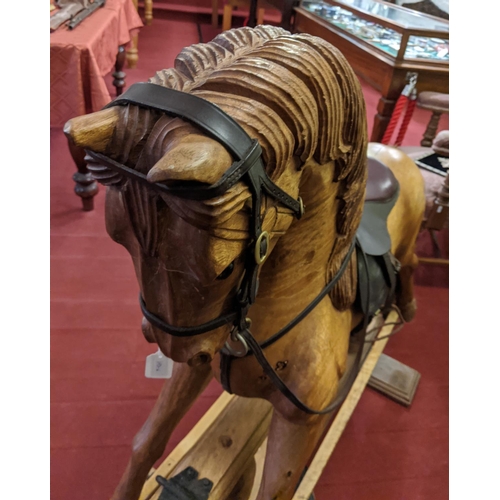 253 - A large carved hardwood child's rocking horse with leather saddle and bridle, 105cm high.