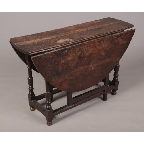 266 - An 18th century oak plank top gateleg dining table. With single drawer having original wrought iron ... 