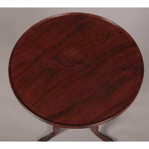 284 - A George III mahogany dish topped tripod wine table. Raised on a gun barrel column over three cabrio... 