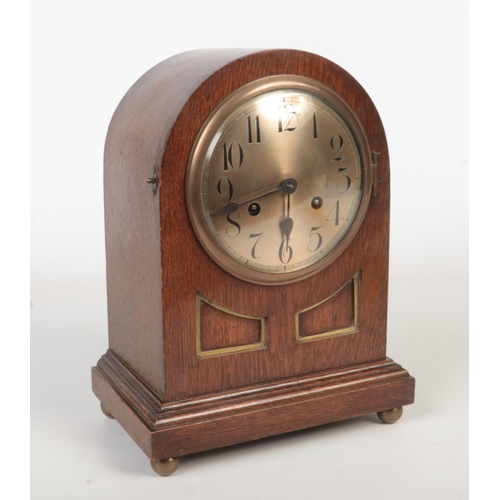 63 - An Edwardian oak cased dome top mantel clock. With silvered dial having Arabic numeral markers. Hous... 