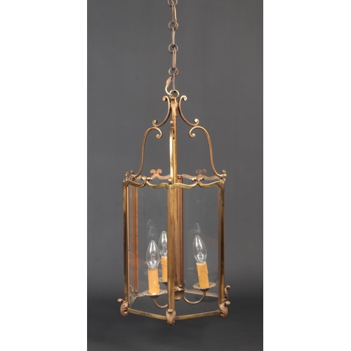 83 - A hexagonal brass and glass three branch hall lantern. With double scrolling pediment and cast scrol... 