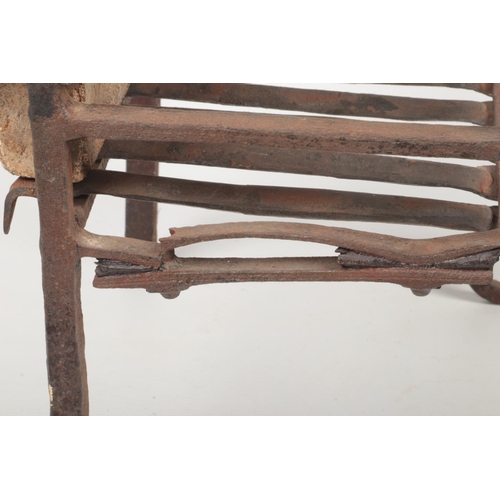 80 - An 18th century wrought iron fire grate. The arch top back decorated in relief with a figure and rai... 