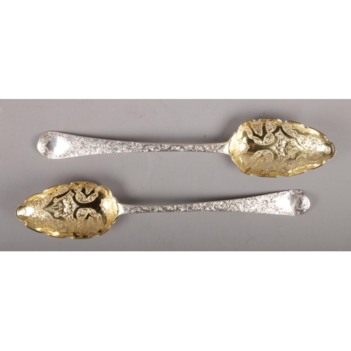 311 - A pair of George III silver berry spoons, with chased decoration and gilt bowls assayed London 1787,... 