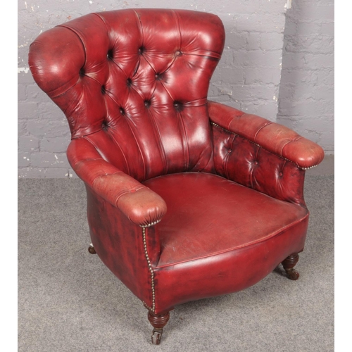 447 - A deep and shallow buttoned red ox blood leather armchair.