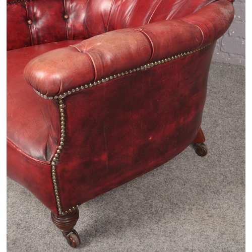 447 - A deep and shallow buttoned red ox blood leather armchair.