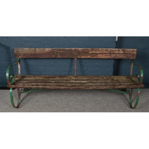 363 - A vintage wood and iron garden bench with scrolling supports. (Length 187cm).