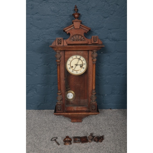 386 - Two wooden wall mounted pendulum clocks, comprising of a Pendulum clock which is decorated with a sh... 