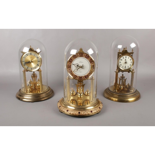 99 - A Kern Lancel Anniversary brass torsion 400 day clock, under glass dome, to include a Koma and one o... 