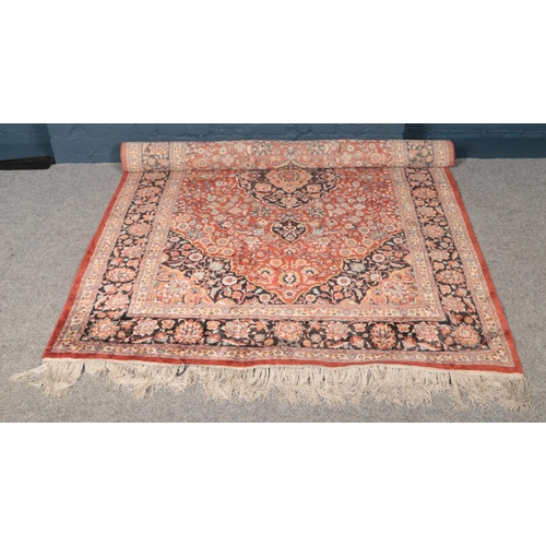 413 - A red ground wool rug with central medallion design. (242cm x 155cm). This rug is hand- knotted.