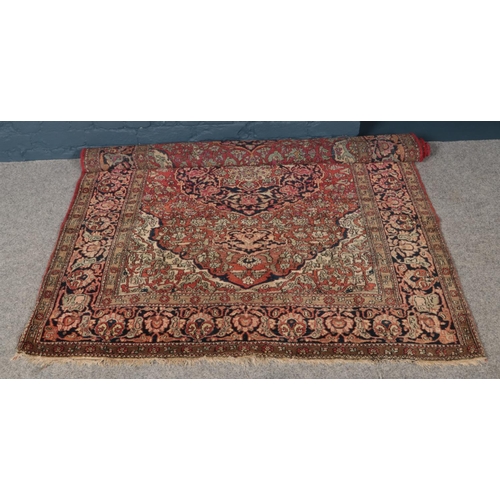 415 - A red ground wool carpet with central medallion design. (210cm x 145cm). This rug is handwoven.