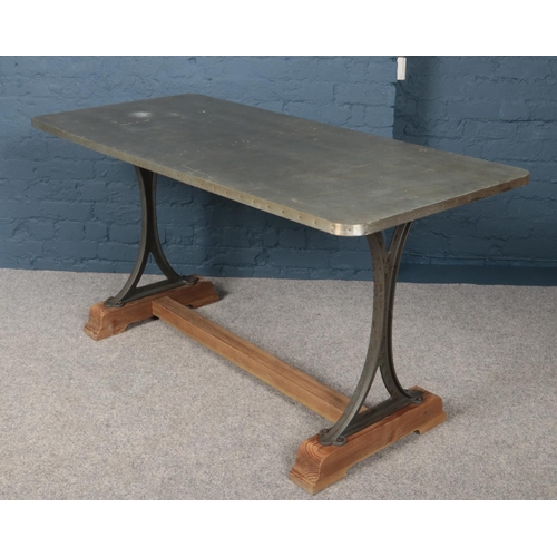 429 - An industrial style table with iron supports, mounted to wooden base.